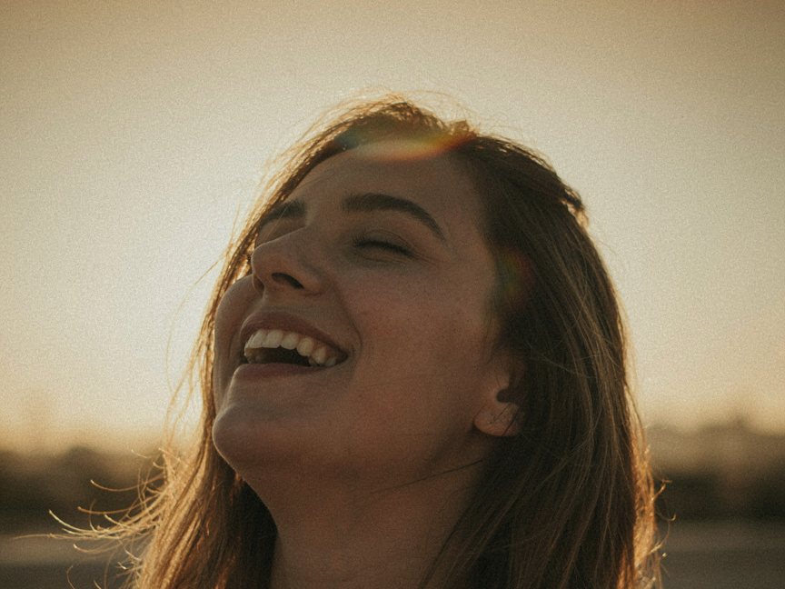 A woman laughing with her head tipped back in low golden sunlight